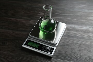 Laboratory scale with flask of sample on wooden table