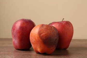 Many rotten red apples on wooden table
