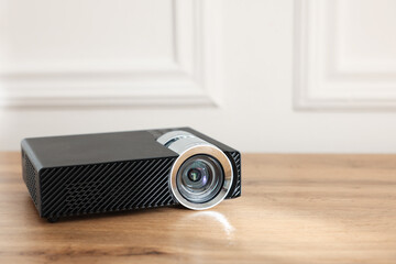 Modern video projector on wooden table indoors, closeup. Space for text