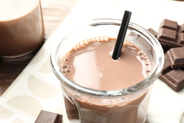 Chocolate milk in glass and ingredient on wooden table, closeup