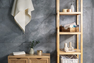 Clean waffle towels and other bath products near grey wall in bathroom
