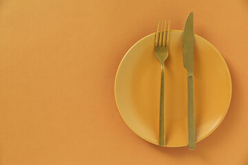 Stylish plate and cutlery on orange background, top view. Space for text