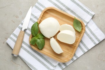 Plakat Pieces of delicious mozzarella cheese, basil leaves and knife on grey textured table, top view