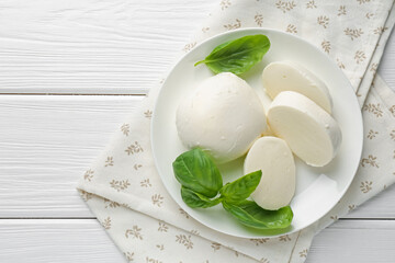 Pieces of delicious mozzarella cheese and basil on white wooden table, top view