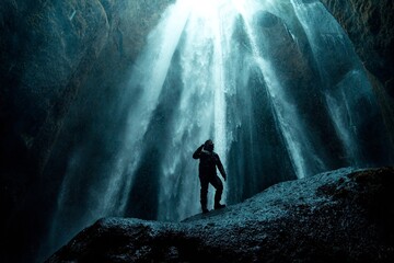 Man in rain gear inside hidden Glj&uacute;frab&uacute;i cave waterfall
