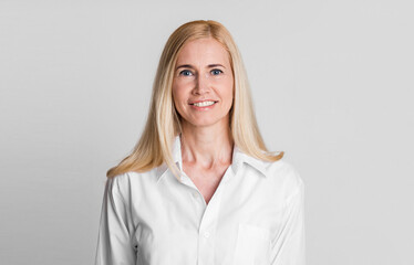 Natural Beauty. Smiling middle-aged female manager in white shirt posing to camera isolated over...