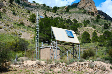 Remote solar panel station in mountainous landscape under clear sky