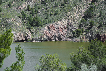 Fototapeta premium Serene rocky lakeside with lush greenery and tranquil waters