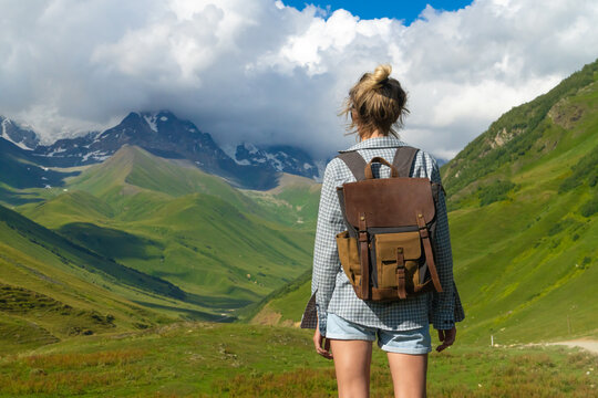 Female hiker with backpack enjoying stunning view of snow-capped mountains and green valleys in the svaneti region of georgia, showcasing the beauty of nature and the spirit of adventure