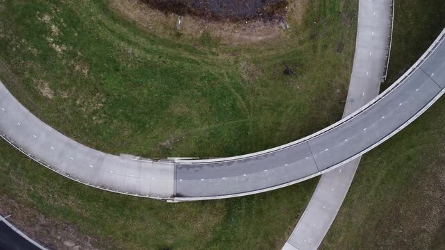 Drone slowly flying up revealing a cyclist riding a bicycle loop.