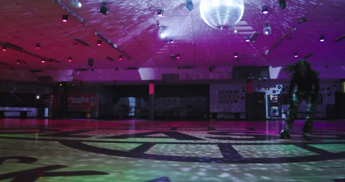 Lone female roller skater doing backwards crouching move but falling and smiling 