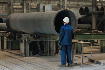 Worker examines new cast iron pipe in factory