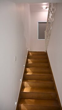 Smooth video shot moving toward white stairs illuminated by warm electric light, featuring white railing inside a bright, minimalist villa with clean white walls and a calm, modern atmosphere.







