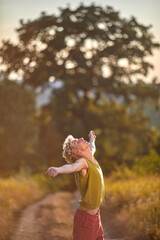 Joyful person enjoying nature on a sunny path surrounded by greenery in the evening light