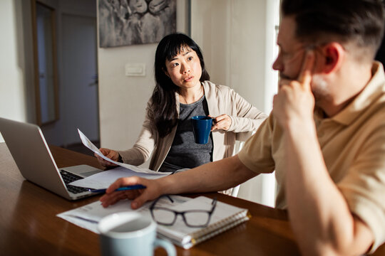 Couple discussing finances at home with laptop and bills on the table