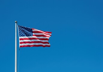 Fototapeta premium Stars and stripes of the USA flag set against a sunny blue sky