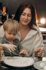 Mother and toddler enjoy cozy family moment while drawing in flour on kitchen table capturing the warmth of slow living playful creativity and emotional connection in early childhood memories