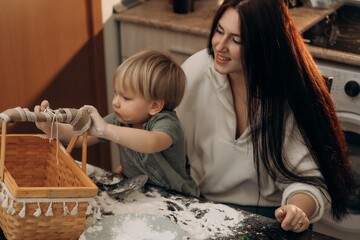 A young boy draws in flour with his mom beside him, sharing a tender moment of messy play that supports emotional development, creativity, and the joyful rituals of everyday parenting at home