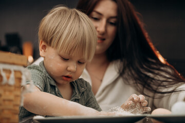 Early childhood moment of gentle parenting as mother and son playfully explore flour and creativity at the kitchen table during messy play that celebrates home rituals and everyday connection