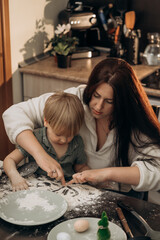 A toddler explores textures and shapes with mom by drawing in flour on a kitchen table, enjoying creative sensory play and bonding during a calm cozy moment of imagination and family warmth