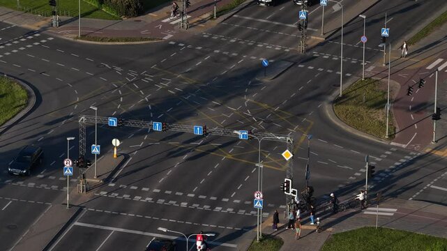 Aerial perspective of a multi-lane city intersection in Vilnius with traffic lights, pedestrian crossings, cyclists, and modern road infrastructure during daylight.