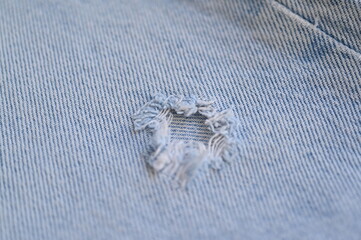 torn light grey denim surface, denim fringe , hole macro texture of blue denim, torn blue denim...