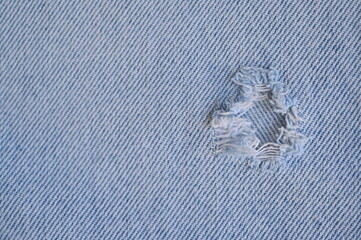 torn light grey denim surface, denim fringe , hole macro texture of blue denim, torn blue denim texture as background photo close up from above	
