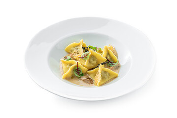 Ravioli with sauce decorated with greens in plate isolated on white background. Italian dishes, top view, close up