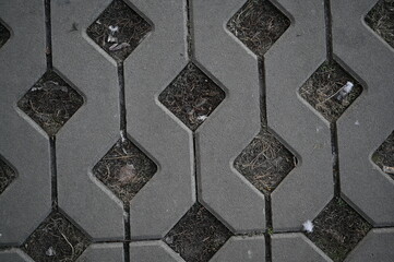 Background texture of square tiles made of gray natural stone. Concrete street covering of road, geometric paving pattern, green lawn and eco parking, green parking, sustainable development city	
