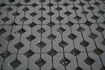 Background texture of square tiles made of gray natural stone. Concrete street covering of road, geometric paving pattern, green lawn and eco parking, green parking, sustainable development city	
