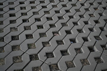 Background texture of square tiles made of gray natural stone. Concrete street covering of road, geometric paving pattern, green lawn and eco parking, green parking, sustainable development city	
