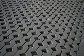 Fototapeta premium Background texture of square tiles made of gray natural stone. Concrete street covering of road, geometric paving pattern, green lawn and eco parking, green parking, sustainable development city 