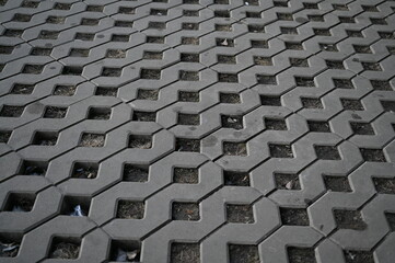 Background texture of square tiles made of gray natural stone. Concrete street covering of road, geometric paving pattern, green lawn and eco parking, green parking, sustainable development city	

