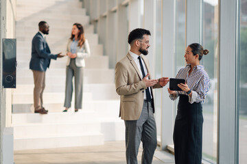 Business colleagues discussing work using digital tablet in modern office