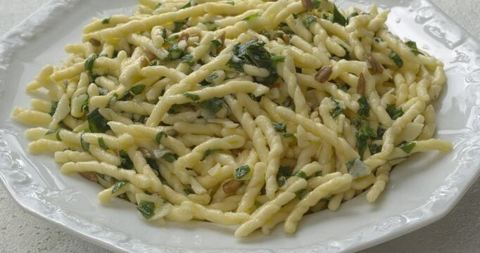 Trofie al Pesto. Trofie pasta with rustic (roughly chopped) pesto on a plate, copy space. Table spin.