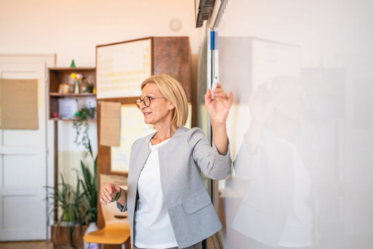 mature woman teacher stand at whiteboard in classroom