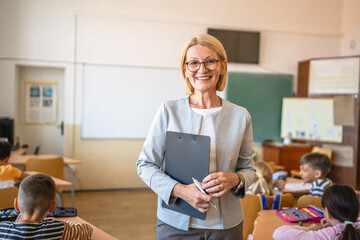 Portrait of beautiful mature woman teacher stand in classroom