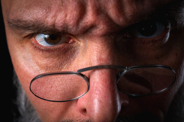 Funny close-up portrait of a quirky bald man with a long gray beard and eyeglasses, making a silly face. Concept of eccentricity, humor, and expressive personality.