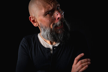 Funny close-up portrait of a quirky bald man with a long gray beard and eyeglasses, making a silly face. Concept of eccentricity, humor, and expressive personality.