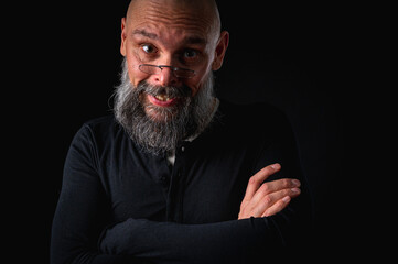 Funny close-up portrait of a quirky bald man with a long gray beard and eyeglasses, making a silly face. Concept of eccentricity, humor, and expressive personality.