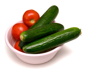 Bright red tomatoes and crisp cucumbers in a ceramic bowl on a table, prepared for a healthy fresh salad.