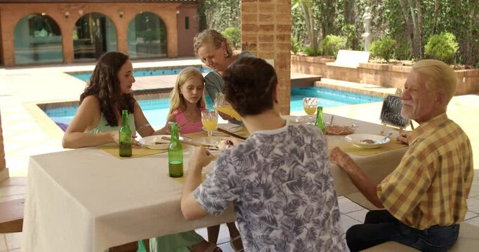 Mature woman serving juice to her family at nice outdoor fathers day lunch..