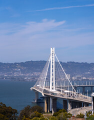 Fototapeta premium The Bay Bridge spans the water under a blue sky, carrying traffic.