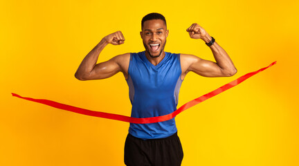 Male Athlete. Happy afro guy crossing the finish line, making winner gesture, breaking red tape,...