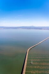 Aerial view of a long bridge stretching across a body of water under a clear blue sky.
