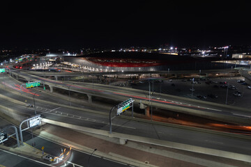 Night view of Boston airport with light trails from cars on the highway.