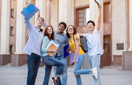 Portrait of excited international high school students raising hands up in the air after passing exam successfully