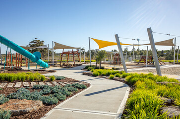 A well-designed public playground in suburban Australia, featuring large shade sails, and...