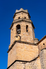 Fototapeta premium A tall, stone church bell tower rises against a clear blue sky.