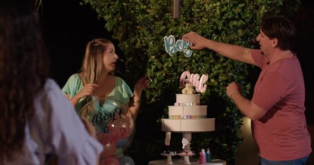 Young cheerful couple posing for photos at their baby's gender reveal party. - Powered by Adobe